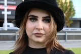 A young woman in a black hat and black top.