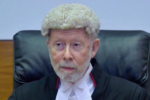 Justice Peter Barr wears a wig and is wearing a black judge's robe.