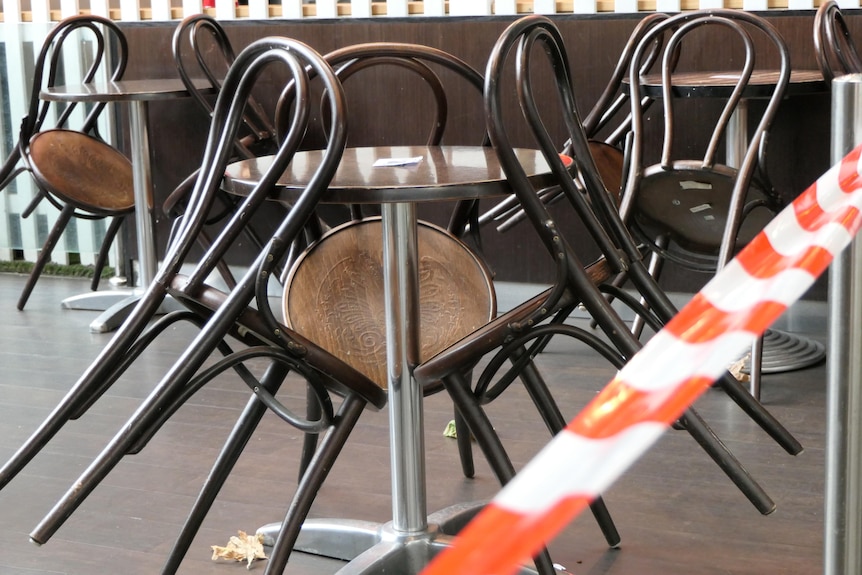 Sillas apoyadas contra una mesa en un café al aire libre.