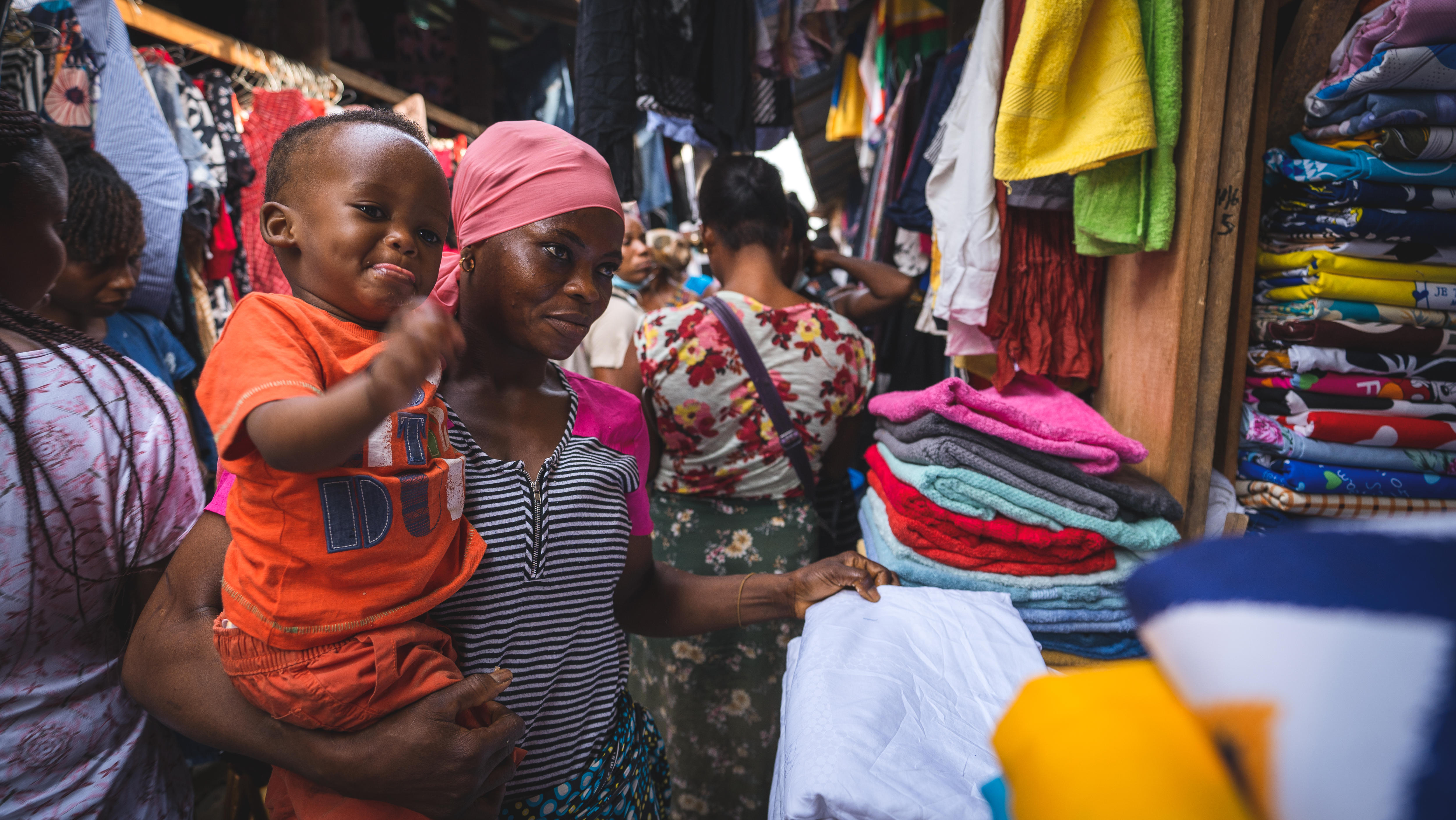 A woman holds her son in a clothing market.