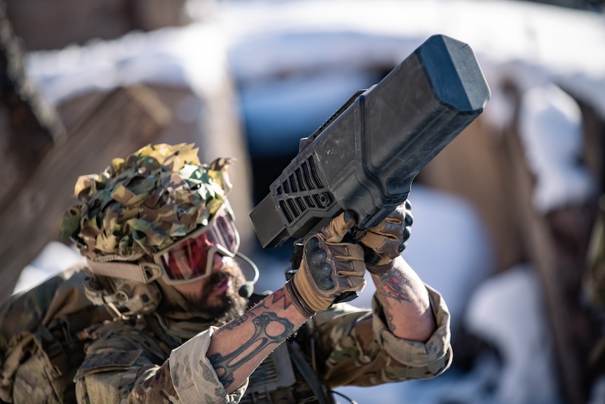 Un soldat avec un drone de la taille d'un très gros pistolet