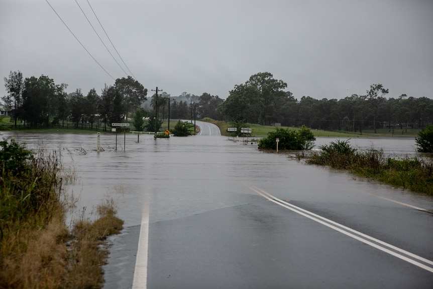 A road is swallowed by water as a creek overflows