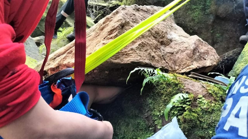 a man's leg stuck in a rock as emergency services try to assist