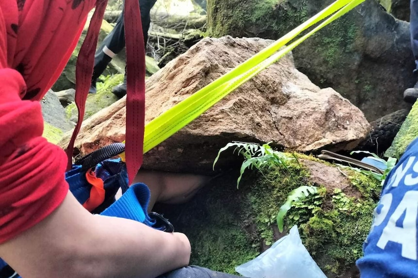 a man's leg stuck in a rock as emergency services try to assist