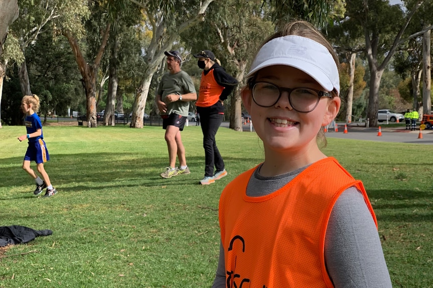 11-year-old Isobel smiles at the camera while walking in a park.