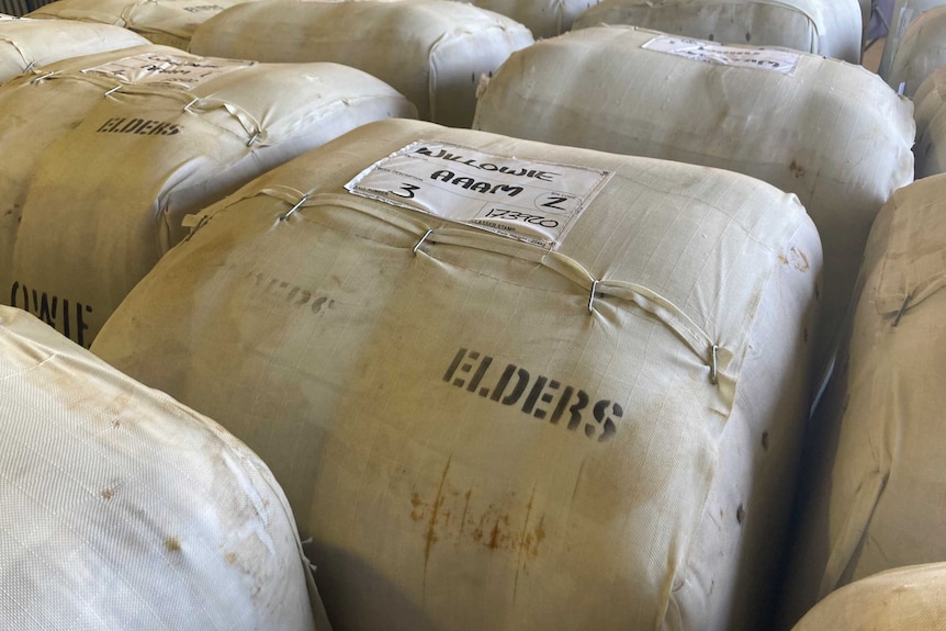 Bales of wool are being stored in a wool shed