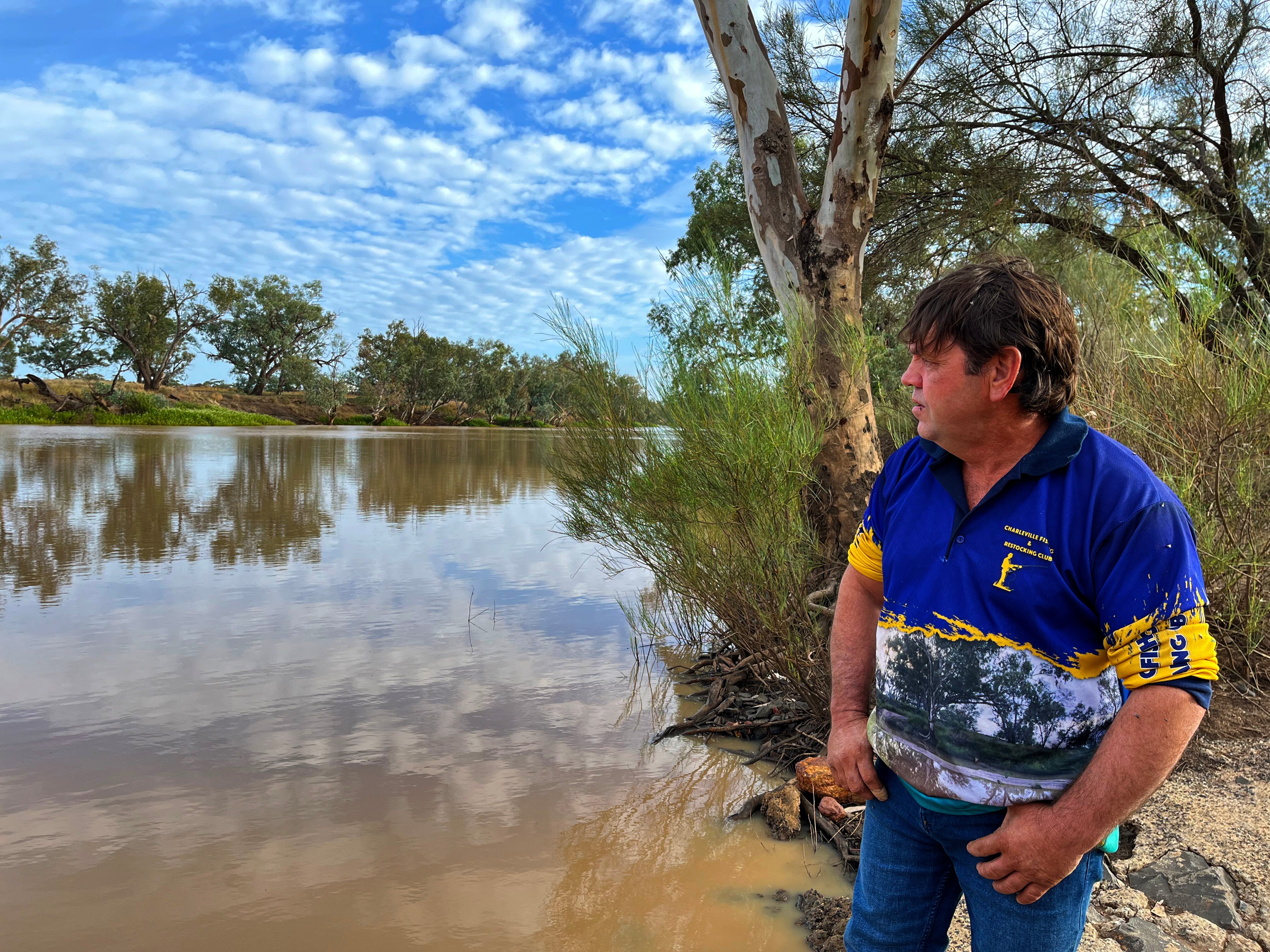 Man in yellow and blue shirt looking over an inland river