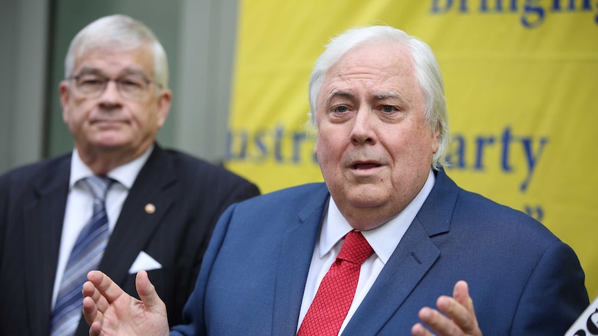 Clive Palmer holds his arms apart speaking at a press conference