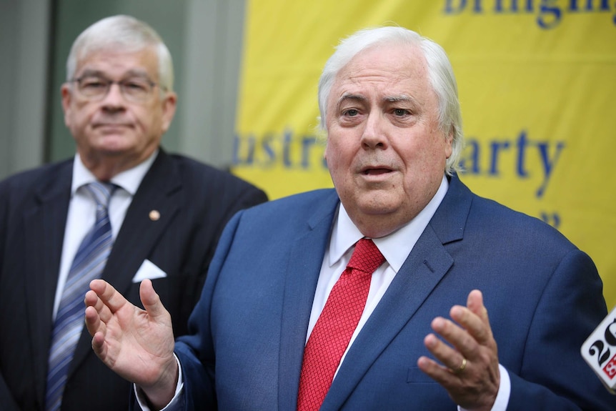 Clive Palmer holds his arms apart speaking at a press conference