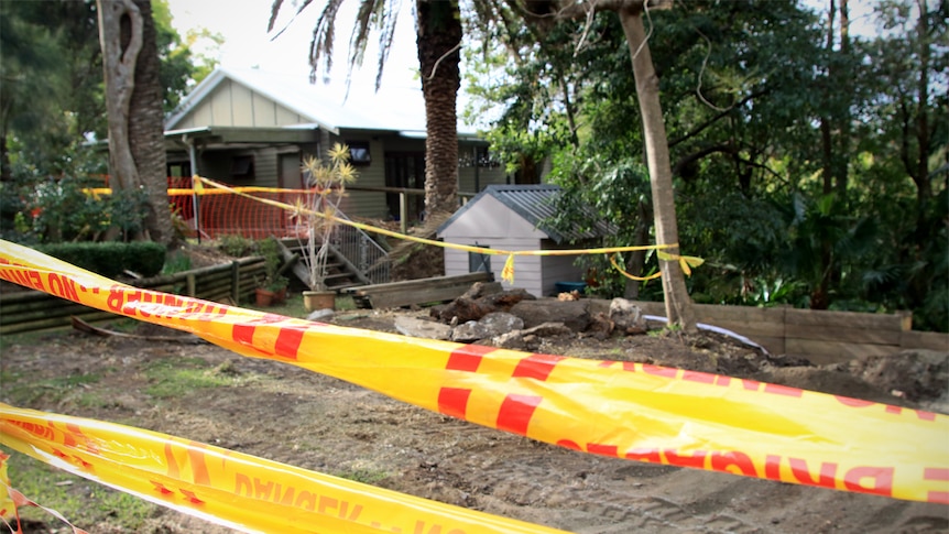 Danger tape tied around trees surrounds a backyard dug up due to a coal wash fire.