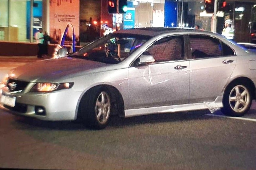 A photo of a silver sedan stationary with a dent in the side.