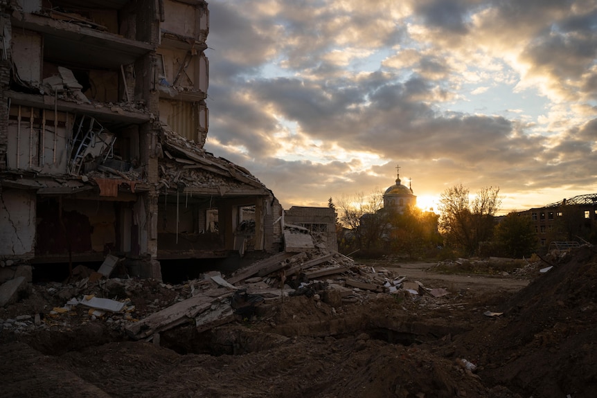Image of a sunset over the remnants of a destroyed building in Ukraine.