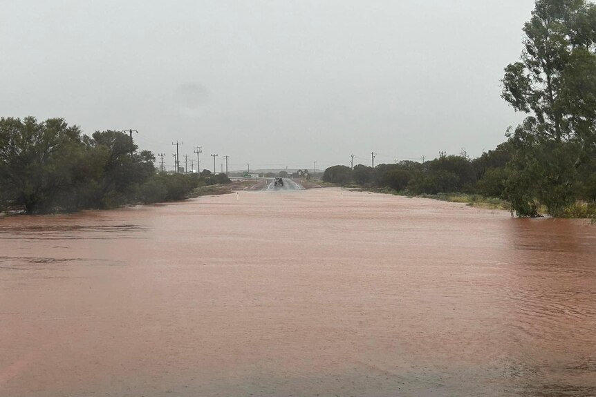 A road into an outback town covered by flood waters.  