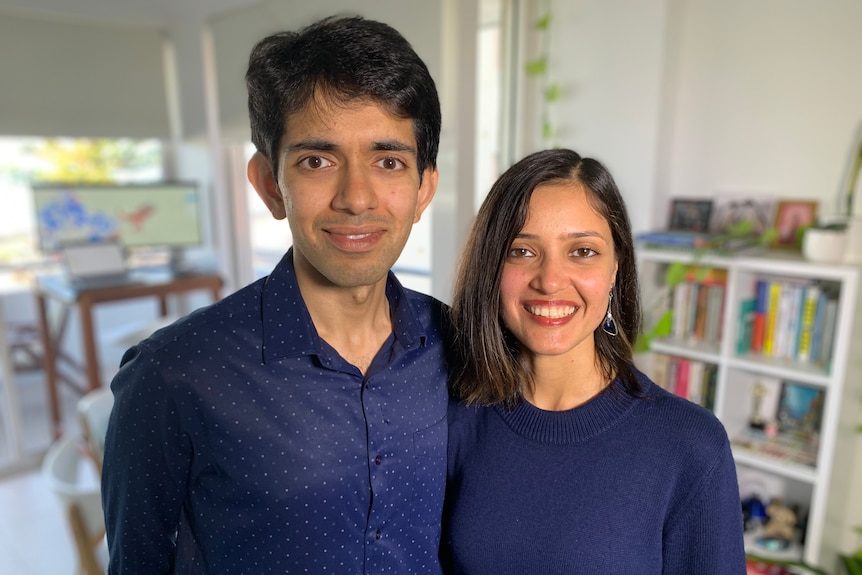 A young Indian couple smile for a portrait while in their Sydney apartment 