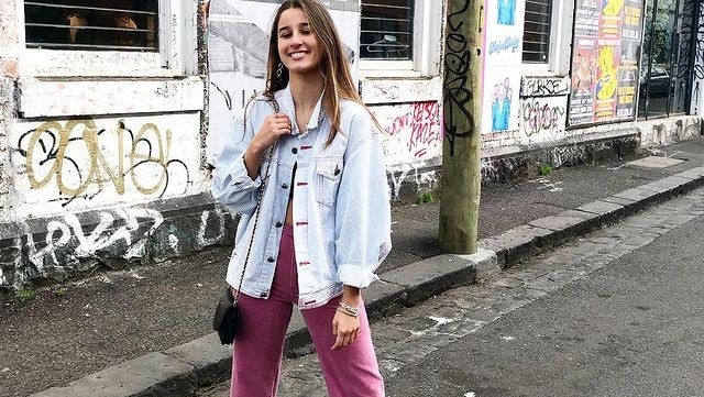 Girl standing on a street in front of a wall with graffiti