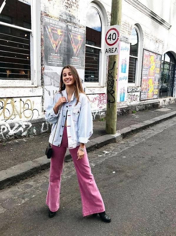 Girl standing on a street in front of a wall with graffiti