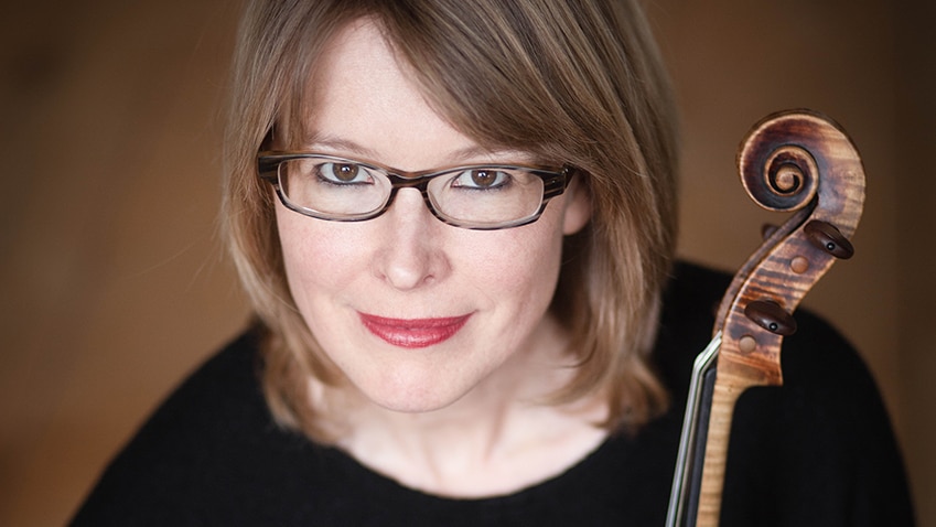 Woman in glasses holding a viola looking up at camera