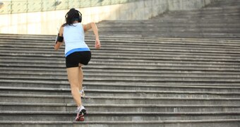 A woman runs up a flight of concrete stairs.