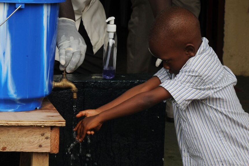 A child washes their hands with chlorine and water in Monrovia, the capital of Liberia.