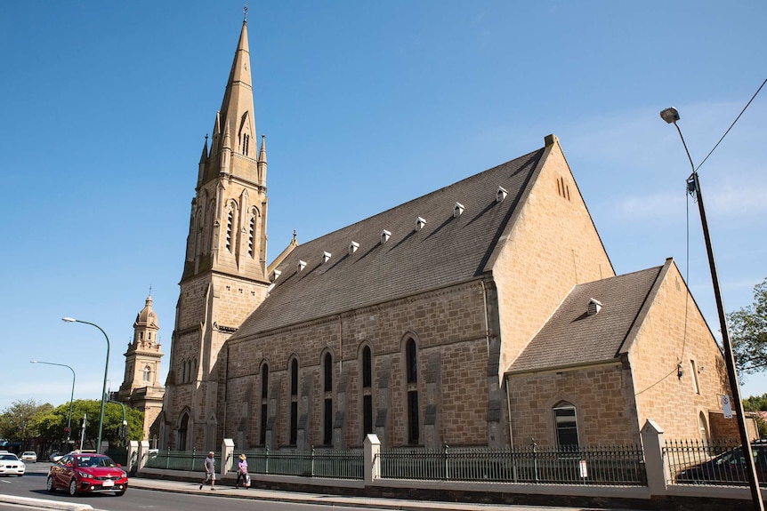 A church and spire rise into a blue sky with another church tower in the background.