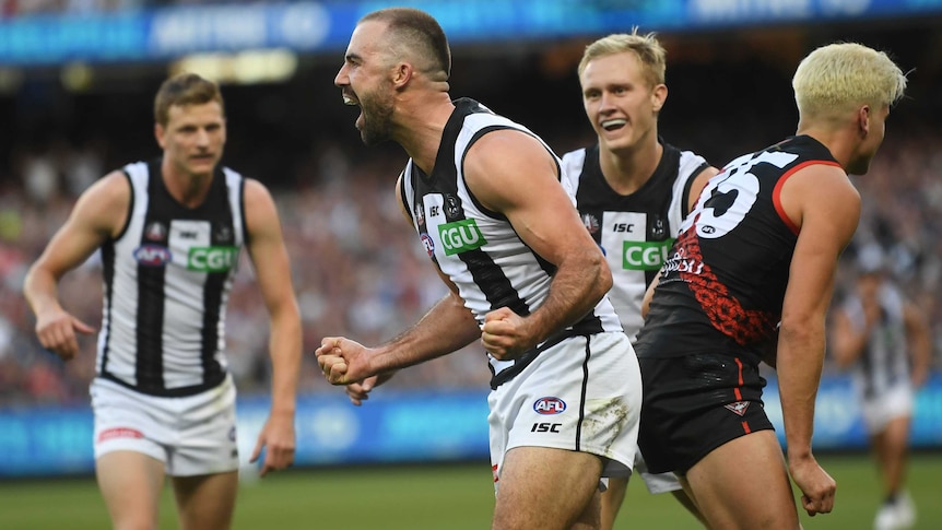 Steele Sidebottom clenches his fists and shouts in celebration as two teammates run towards him