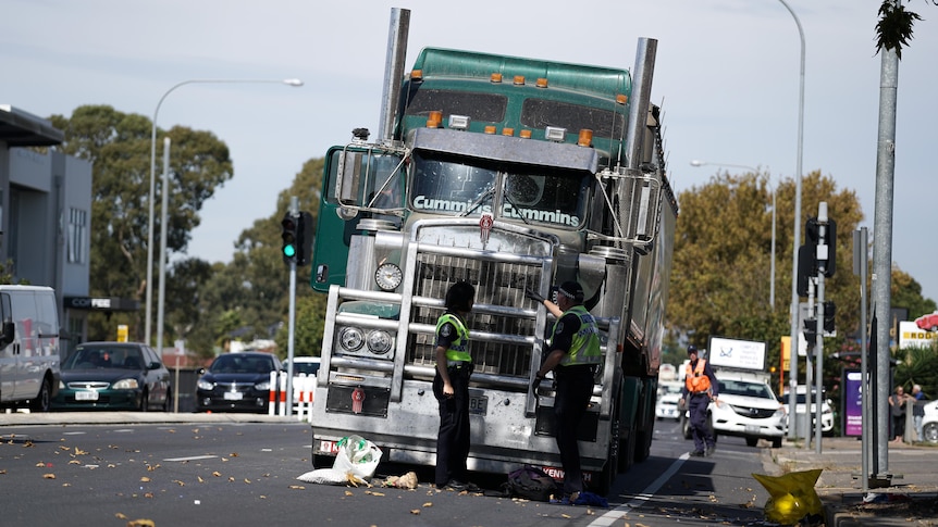 Police officers in front of a stationary truck.