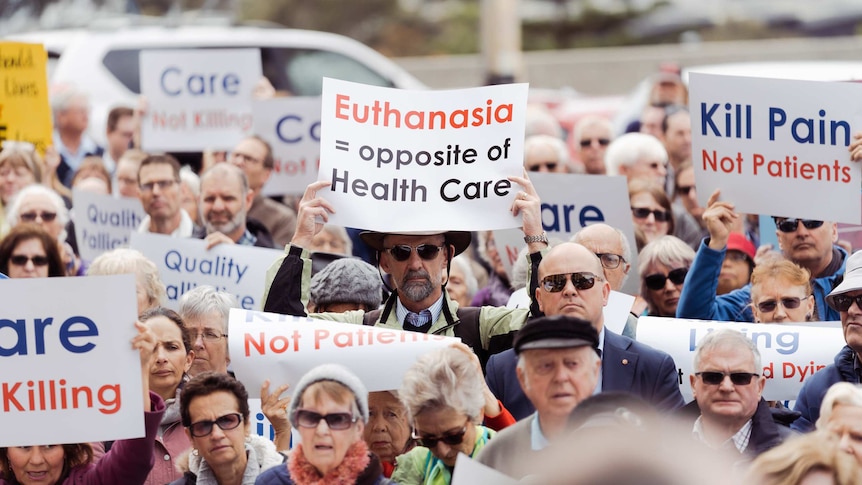 A crowd of people holding up placards protest at a rally outside WA Parliament House against voluntary euthanasia.