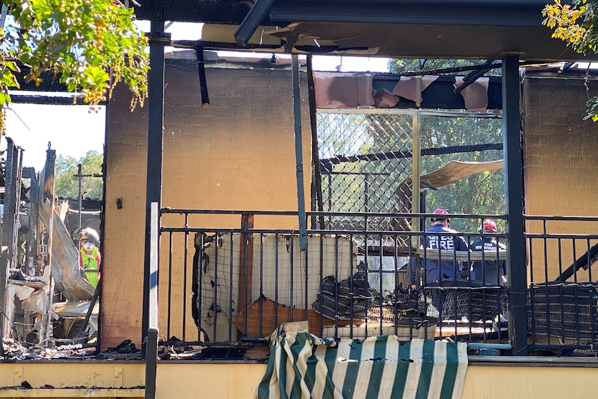 The burnt remains of a home with fire officers in attendance