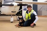 A young man and his dog pose in front of a light aircraft in regional WA.