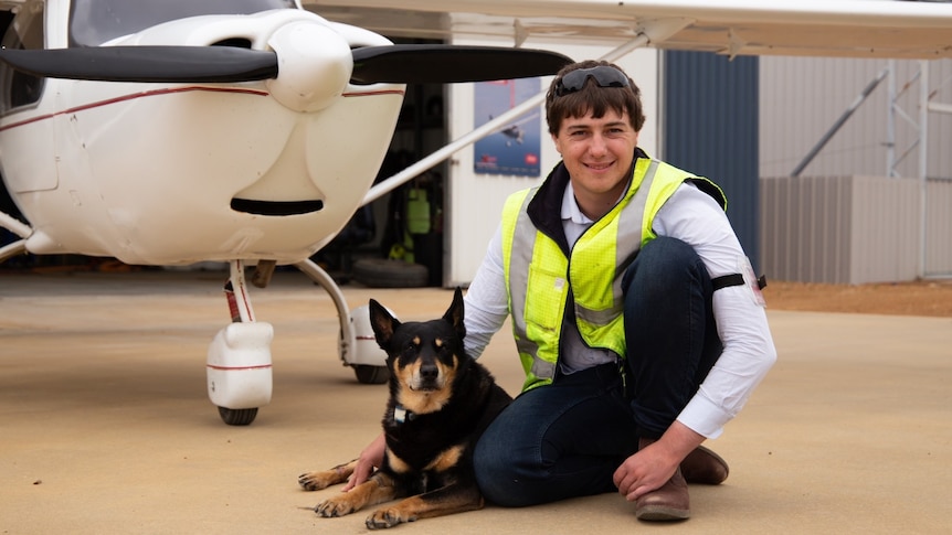 A young man and his dog pose in front of a light aircraft in regional WA.