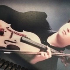 A teenage girl looks very sad while holding a violin