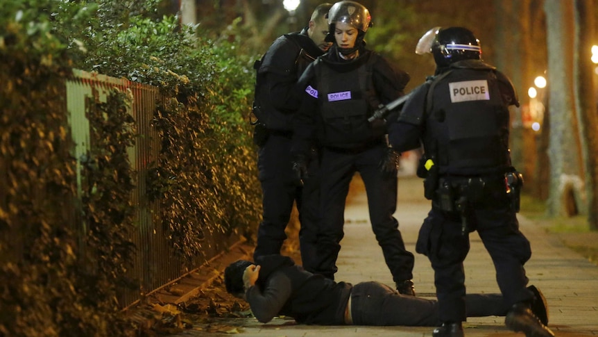 A man lies on the ground as French police check his identity near the Bataclan concert hall