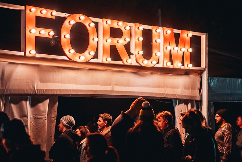 The entrance to the Splendour Forum tent with FORUM lit up in lights at night, 2019