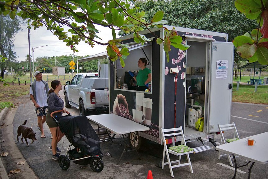 A couple with a dog and pram outside a mobile coffee van in the beachside suburb of Pallarenda, Townsville.