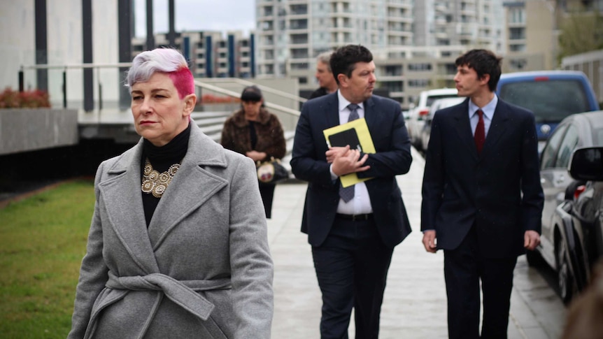 A woman with pink hair walks into court.