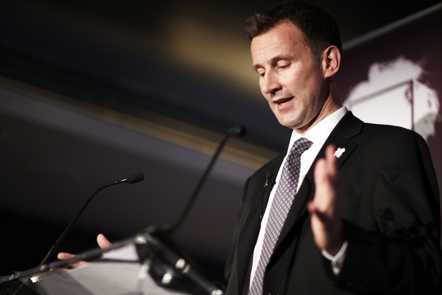 Jeremy Hunt making a speech at a podium with hands spread