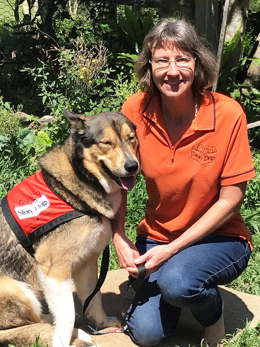 Story Dogs co-founder Janine Sigley kneels alongside her dog Buddy.