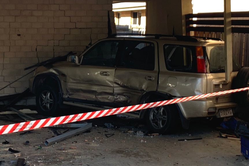 A wrecked car that was hit by a stolen car in a suburban car port 