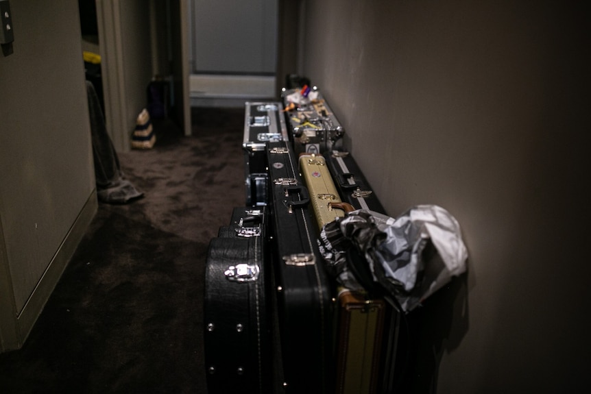 Cases of various sizes and shapes are lined up against a hallway wall.