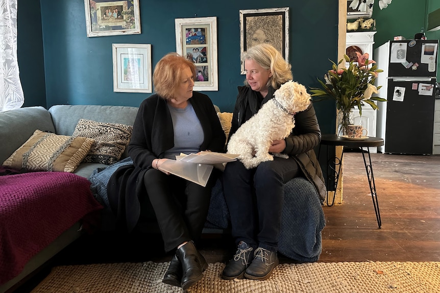 Andrea, Jen and Andrea's dog sitting on couch, looking at documents