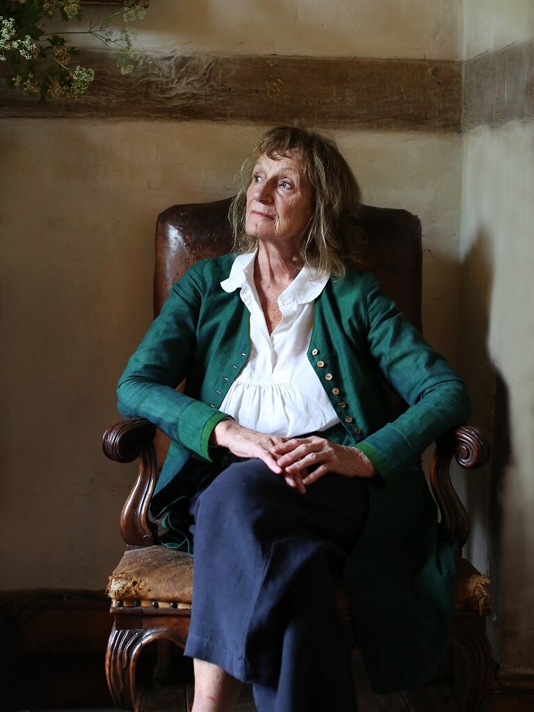 Amanda Feilding sits in a leather chair inside looking out into the distance.