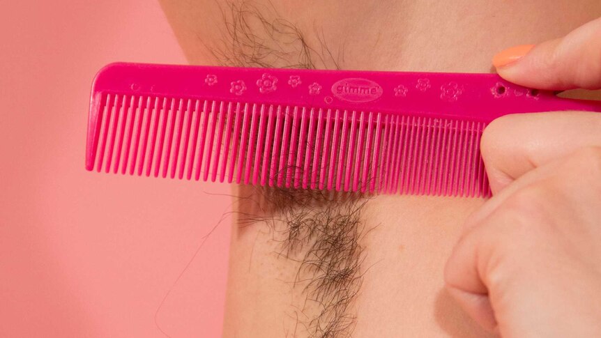 A woman's armpit with her hair grown out, and a comb.