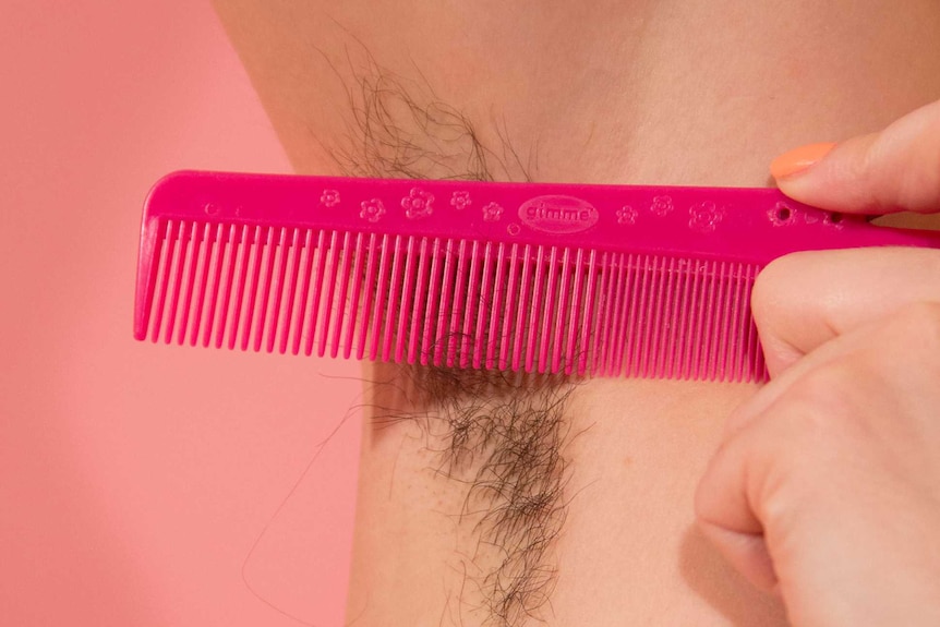 A woman's armpit with her hair grown out, and a comb.