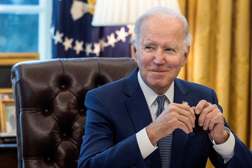 US President Joe Biden sits at his desk in the Oval Office