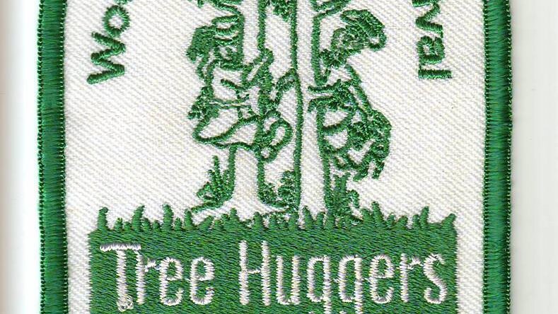 A fabric badge with the word treehugger and an image of people hugging trees embroidered on it.