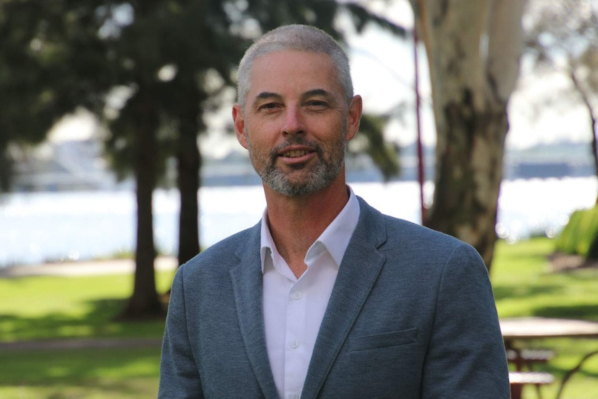 A close up of Andrew Ross amongst trees with a river in the background.