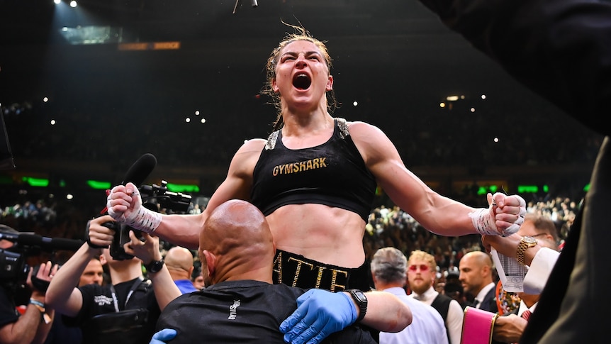 Katie Taylor screams with her arms out to the side as she is lifted up