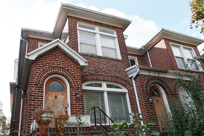 A red brick townhome in a leafy street in Queens.