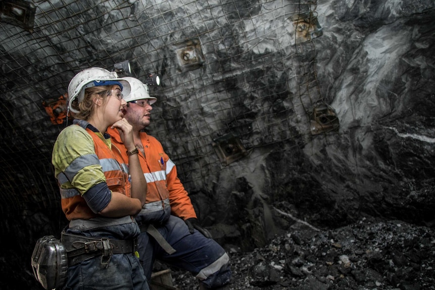 Two geologists standing next to each other having a discussion in an underground gold mine.