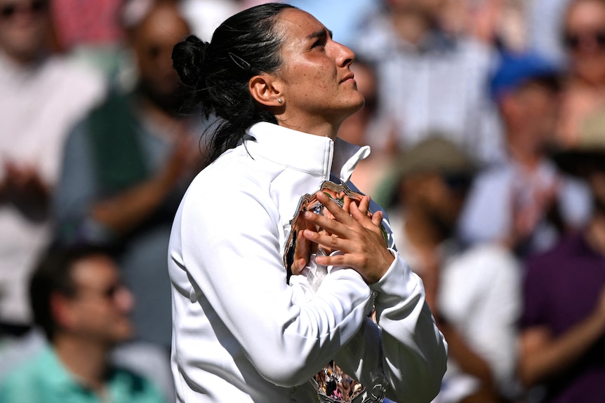 Ons Jabeur clutches a trophy to her chest.